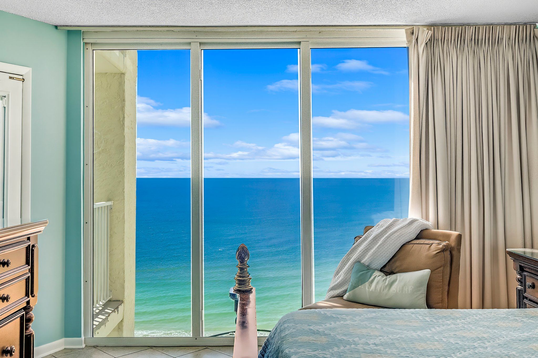 Ein Schlafzimmer mit einer großen Schiebetür, die auf einen Balkon mit Meerblick führt.