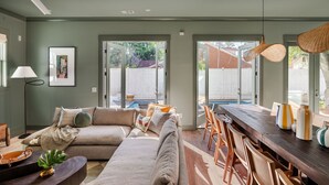 A modern living room with a sectional sofa, dining area, and large windows. - 14BR Luxury Compound | Private Pool, Built-in spa (Savannah)
