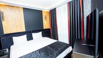 A modern hotel room with a large bed, a flat-screen TV, and a wooden accent wall.