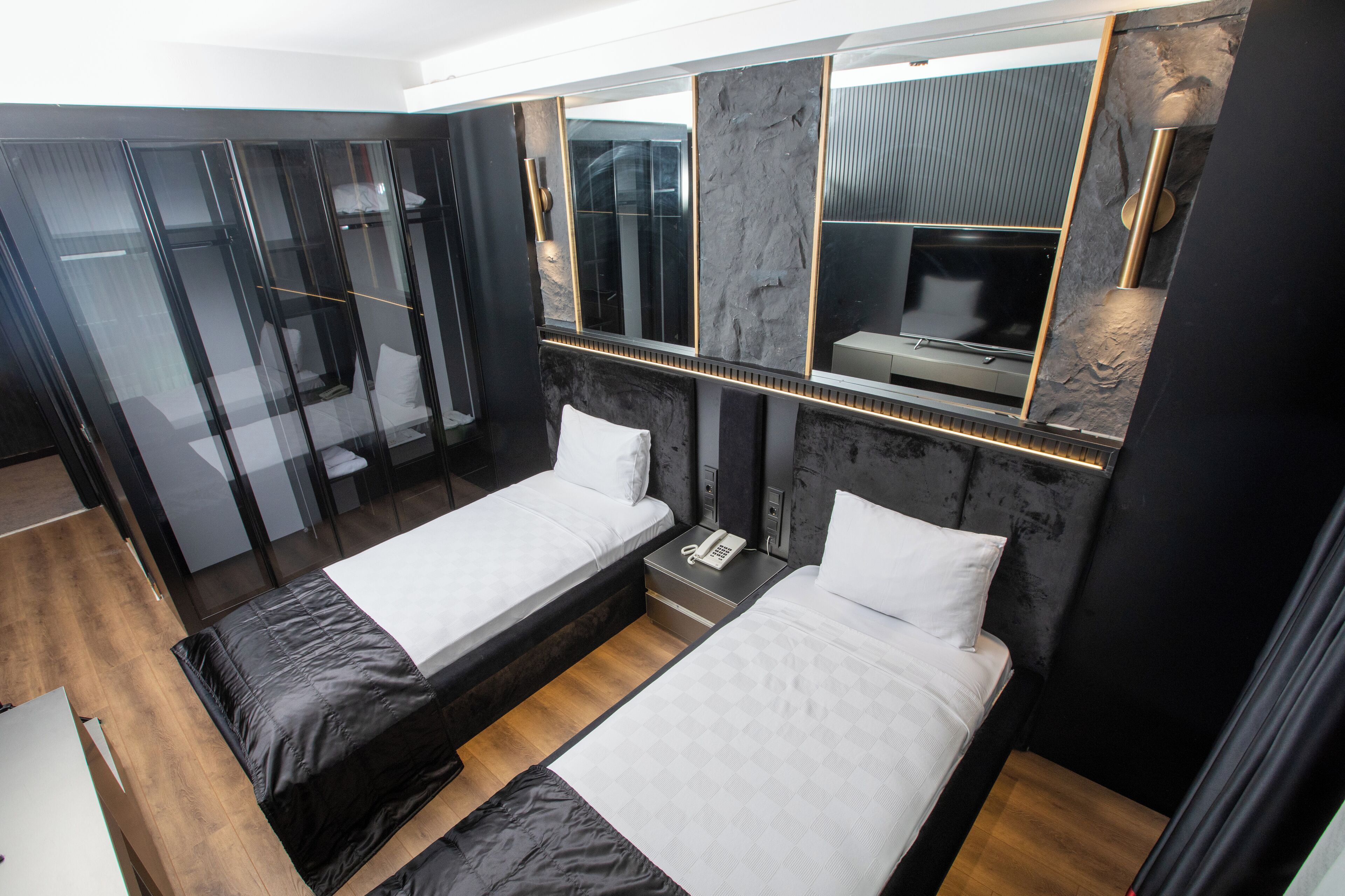 A modern hotel room with two beds, a wardrobe, and a large mirror.