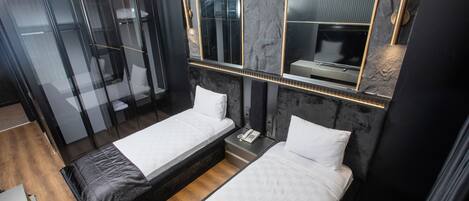 A modern hotel room with two beds, a wardrobe, and a large mirror.