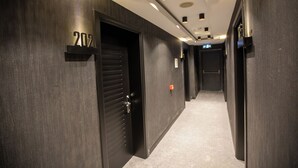 Un pasillo con paredes de madera oscura, una puerta con la leyenda “207” y suelo cubierto de alfombra.