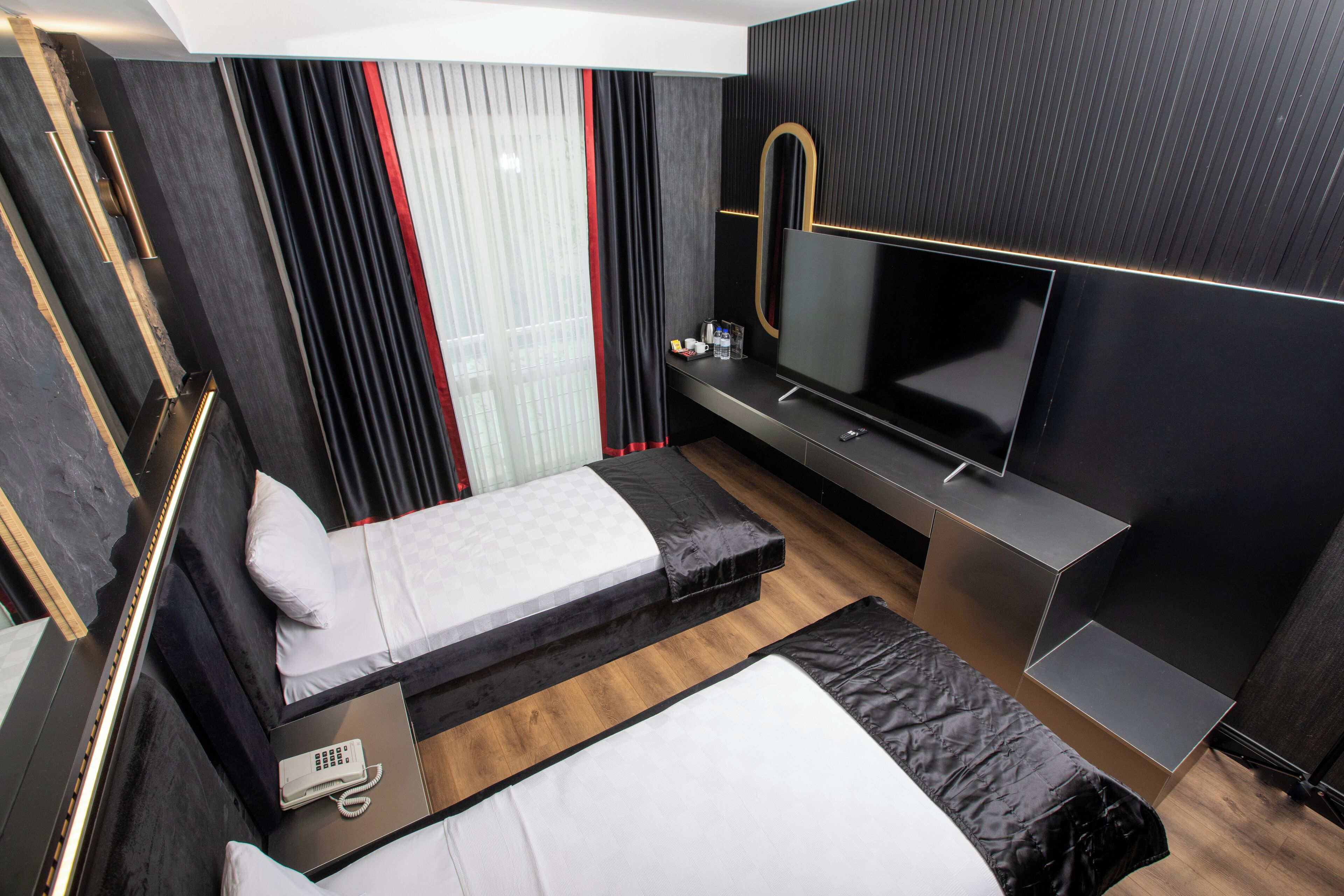 A modern hotel room with a bed, a desk, a TV, and a phone.