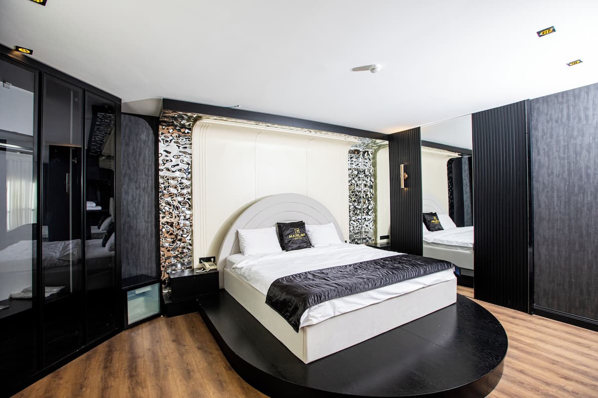 Quarto moderno com cama curva, roupeiro embutido e um espelho grande.