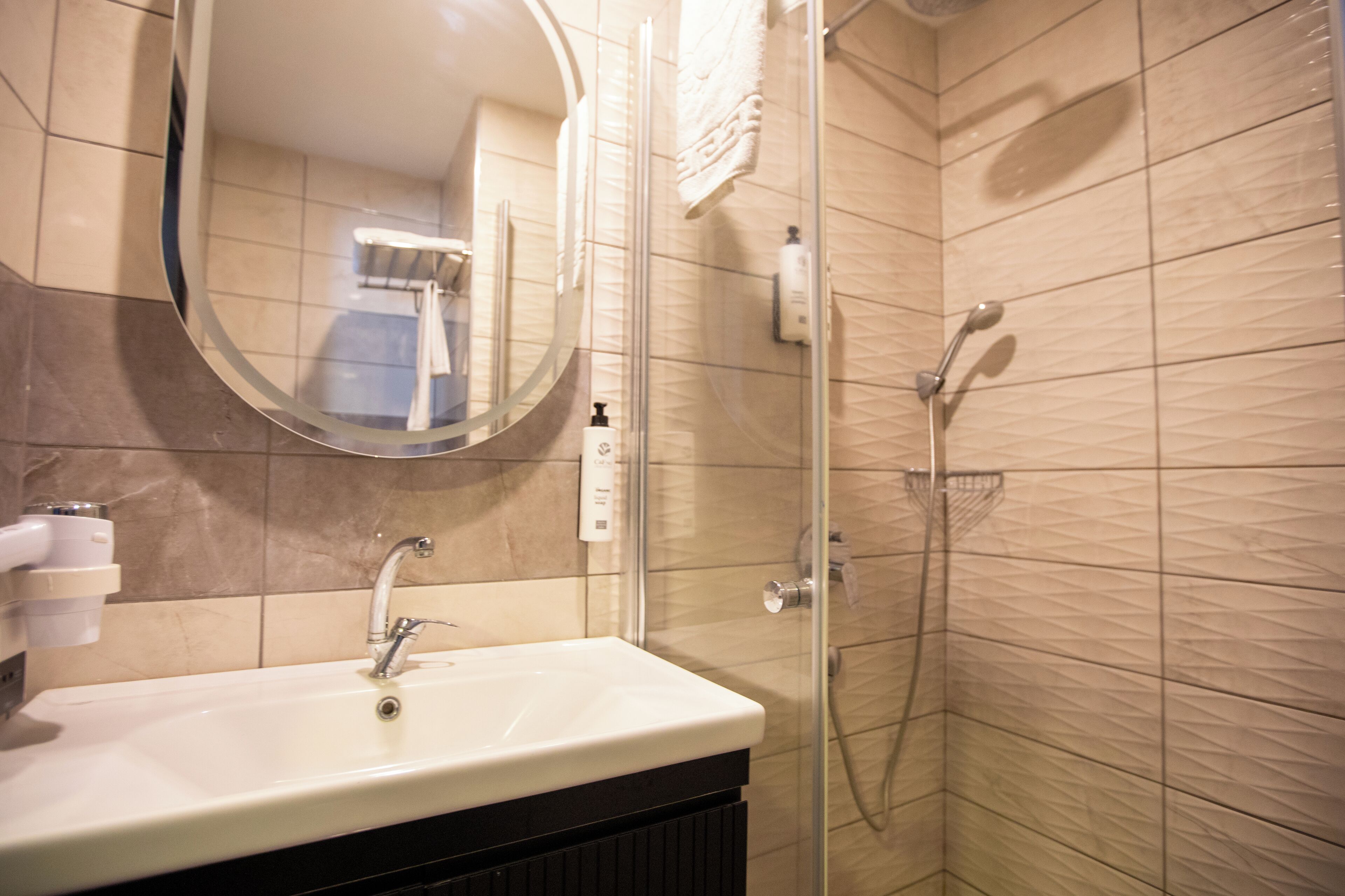 A bathroom with a sink, mirror, and shower.