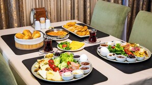 Un bufé de desayuno con diversos platos, como pan, huevos y ensaladas, sobre una mesa con individuales negros.