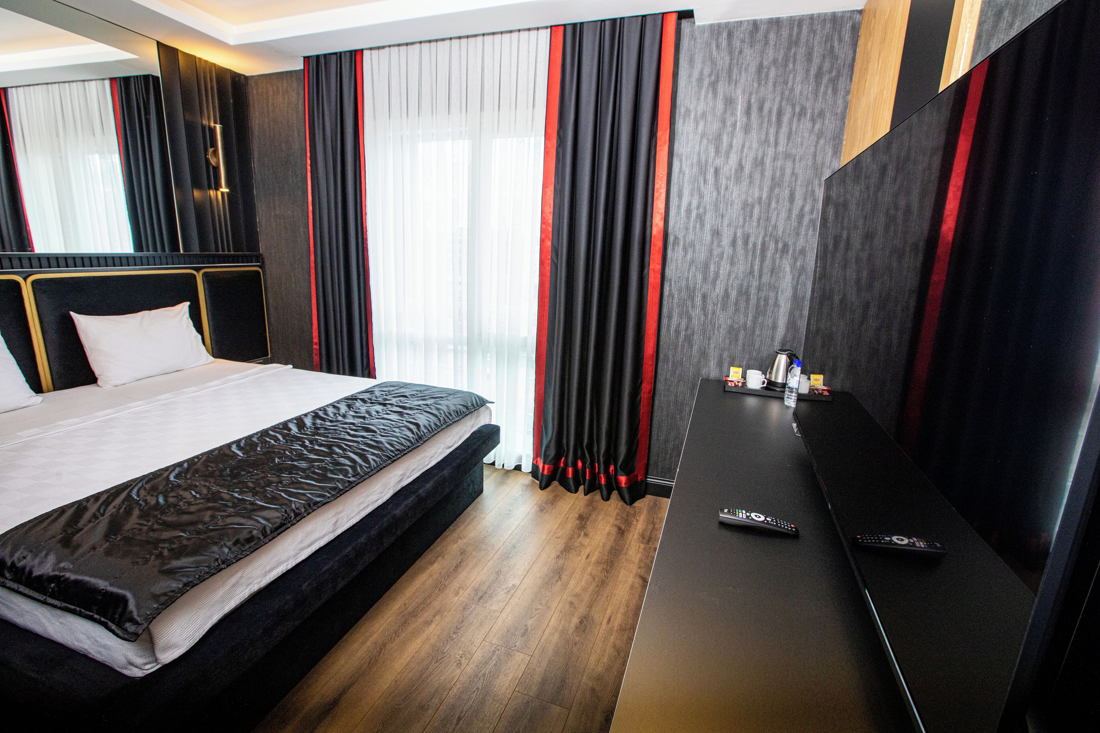 A hotel room with a bed, a desk, and a TV.