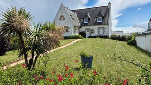 A large, white, two-story house with a steeply pitched roof, surrounded by a well-maintained lawn and flowering plants. - Escapade Bretonne - Binic, beaches and old port. Large garden, high-speed wifi. (Binic-Étables-sur-Mer)