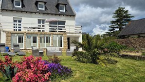 A two-story house with a balcony, stone walls, and a garden with colorful flowers. - Escapade Bretonne - Binic, beaches and old port. Large garden, high-speed wifi. (Binic-Étables-sur-Mer)