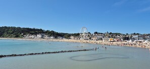 Ein Strand mit Riesenrad, blauem Himmel und felsiger Küste.