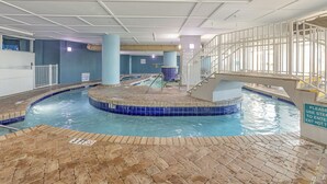 An indoor swimming pool with a tiled edge, a brick floor, and a staircase leading to a higher level. - Spectacular 3 BR 2 BA Ocean Front Condo (Myrtle Beach)