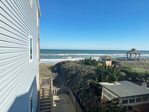 A coastal view with a wooden deck leading to a gazebo overlooking the ocean. - KD1401D- Oceanfront beauty w/stunning ocean views, 2 bedrooms, comm. pool! (Kill Devil Hills)
