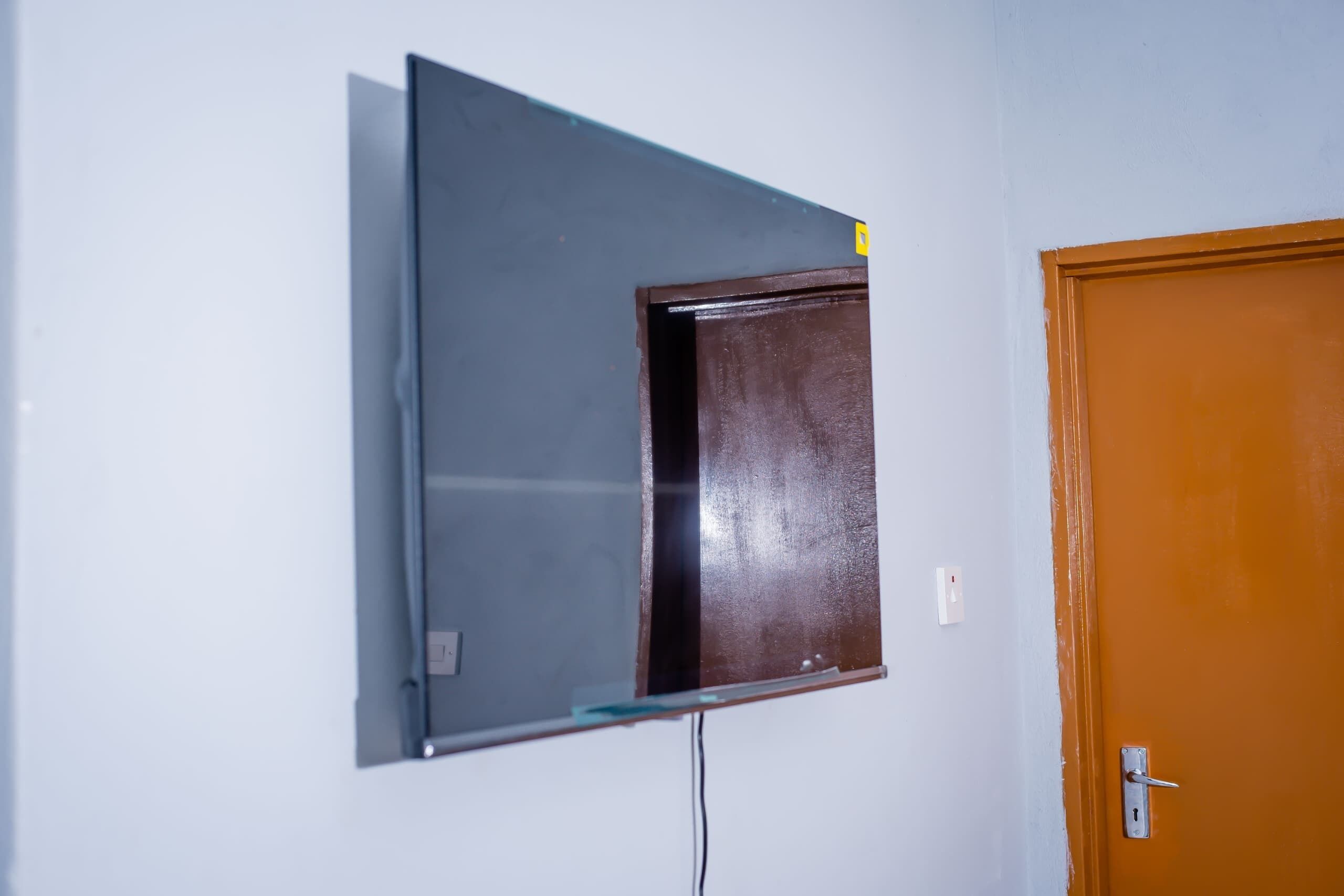 Una habitación con televisión de pared, una puerta y un enchufe.