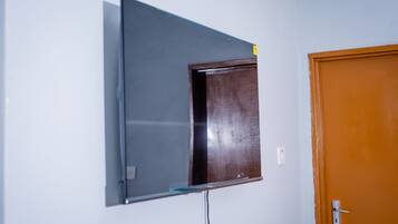 Una habitación con televisión de pared, una puerta y un enchufe.