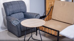 Una poltrona grigia con un tavolino rotondo di legno davanti.