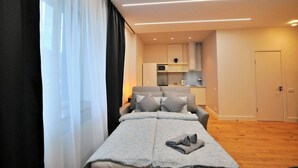 Une chambre d’hôtel moderne équipée d’un lit, d’un canapé, d’une kitchenette et d’une porte.
