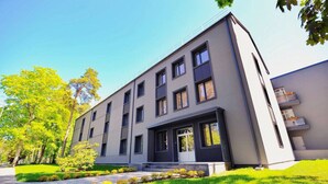 Un bâtiment moderne à plusieurs étages, doté d’un toit plat, de grandes fenêtres et d’une pelouse bien entretenue.