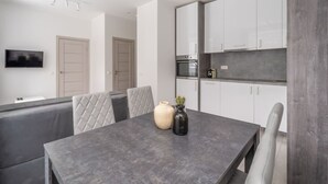 Une cuisine moderne avec des meubles blancs, un four encastré et un plan de travail gris.