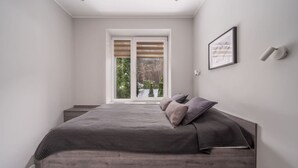 Une chambre à coucher avec un lit, une fenêtre et un luminaire fixé au mur.