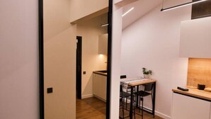 A modern kitchen with wooden flooring, white cabinets, and a dining area with a table and chairs. - Last floor two level apartment with fantastic view (Rīga)