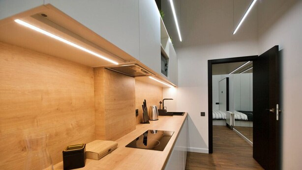 A modern kitchen with a wooden countertop, a built-in stove, and a sink. - Last floor two level apartment with fantastic view (Rīga)