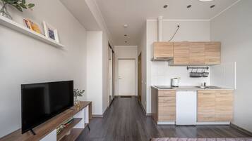 Un espacio habitable pequeño con kitchenette, televisor de pantalla plana y cama.