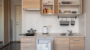 Een moderne keuken met houten kastjes, een ingebouwde oven, een spoelbak en een waterkoker.