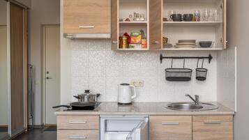 A modern kitchen with wooden cabinets, a built-in oven, a sink, and a kettle.
