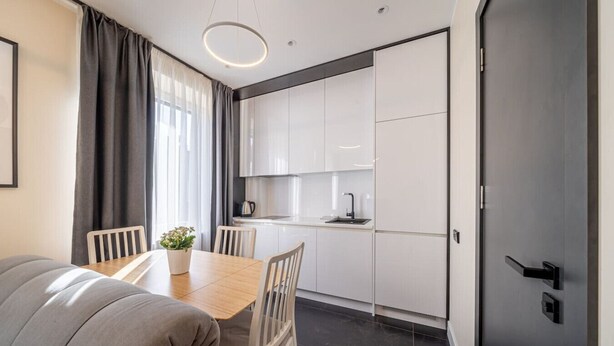 Una cucina moderna con mobili bianchi, un piano di lavoro nero e un lavello in acciaio inossidabile.