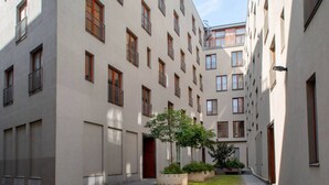 Une cour intérieure avec un bâtiment doté de nombreuses fenêtres et d’un arbre au centre.