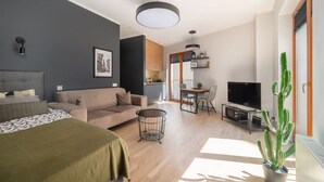 Un salon moderne avec un canapé, une table basse, un téléviseur et un cactus.