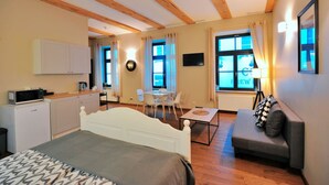 Ein modernes Schlafzimmer mit Bett, einer Couch, einem Esstisch und einer Küchenzeile.