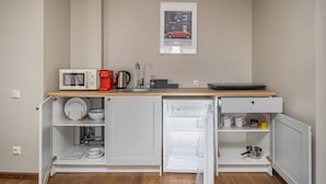 A compact kitchenette with a microwave, coffee maker, kettle, and a small refrigerator.