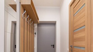 A hallway with a wooden bench, a mirror, and a door. - Dzintaru studio apartment (Jūrmala)