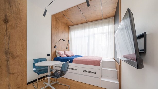 A compact bedroom with a bed, a desk, and a chair.