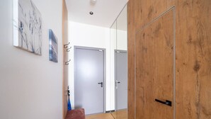 A hallway with a wooden bench, a door, and a wall-mounted artwork.