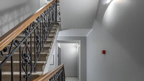 Una escalera con barandilla de madera y barandillas de metal negro, que conduce a un rellano con suelo estampado.