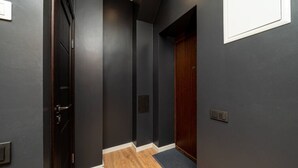 Ein Korridor mit dunklen Wänden, einer Holztür und einem Lichtschalter an der Wand.