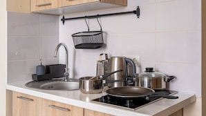 Una cuina moderna amb un rentaplat, fogó i diversos utensilis de cuina.