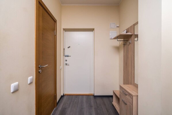 A narrow hallway with a wooden door on the left, a white door at the end, and a wooden cabinet on the right.