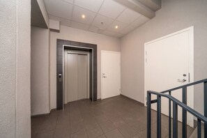 Un pasillo con una puerta, un ascensor y una escalera.