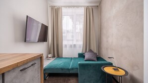 Ein kleiner, moderner Raum mit einem Bett, einem Schreibtisch und einem Fernseher.