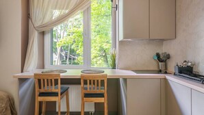 Una cocina con ventana, dos sillas de madera, una encimera y salpicadero.