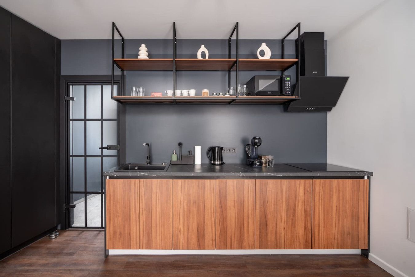 A modern kitchen with a central island, wooden cabinets, and a black countertop.