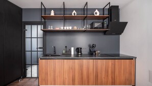 A modern kitchen with a wooden island, black cabinetry, and a built-in microwave. - Top Location – Spacious Bath – New and Cozy (Rīga)