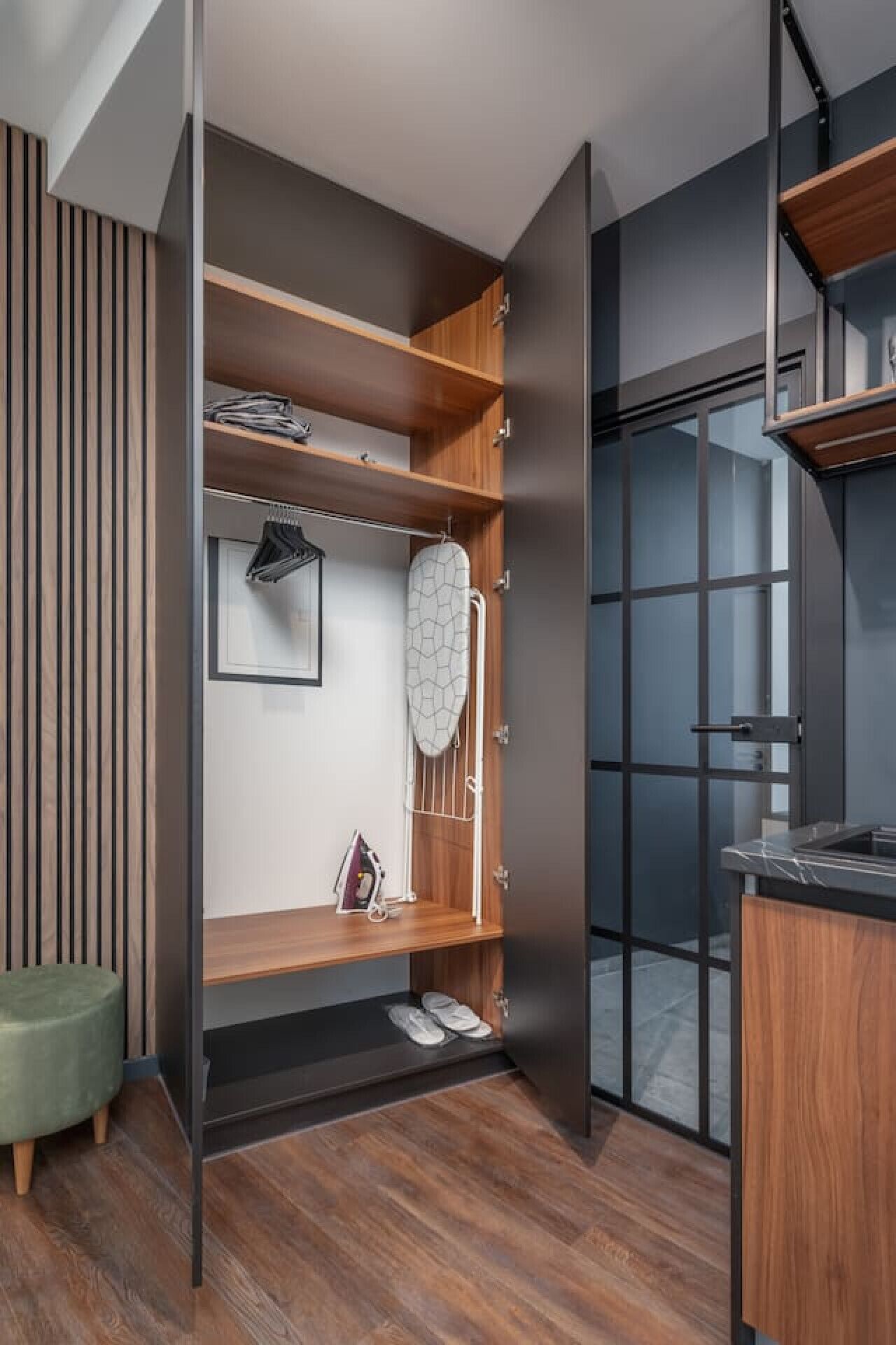 A modern, open-plan living space with a built-in wardrobe, wooden flooring, and a view through a glass door.