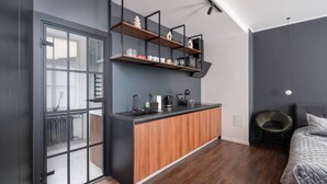A modern bedroom with a built-in kitchen area, a large window, and a cozy seating area. - Top Location – Spacious Bath – New and Cozy (Rīga)