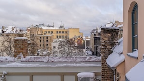 A snowy urban landscape with buildings, a brick wall, and a window with a view of the city.