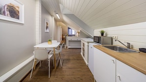 A modern kitchen with white cabinetry, a wooden countertop, and a dining area with a white table and chairs.