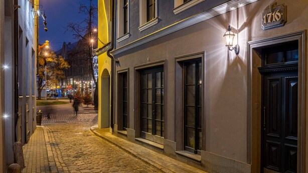 A cobblestone street with a building featuring large windows and a door marked with the number 1716.